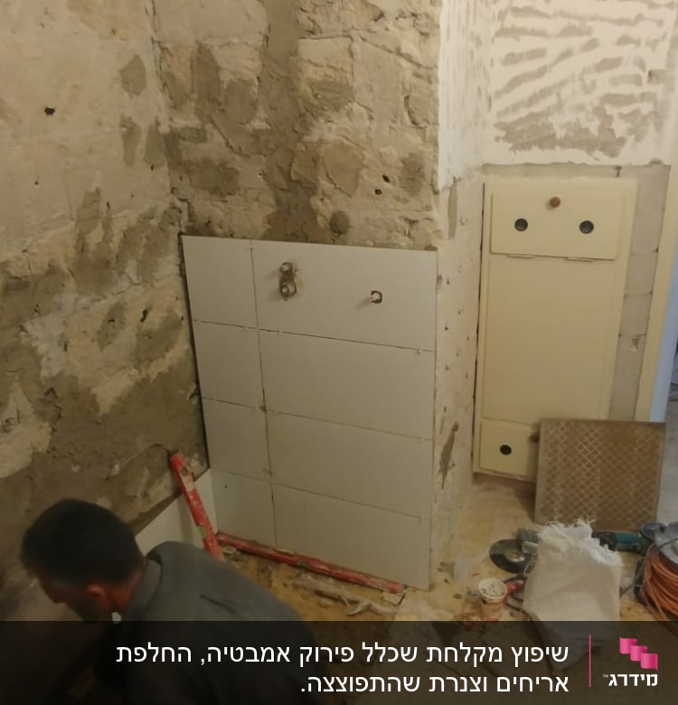 עובד מתקין אריחים על קיר במהלך שיפוץ